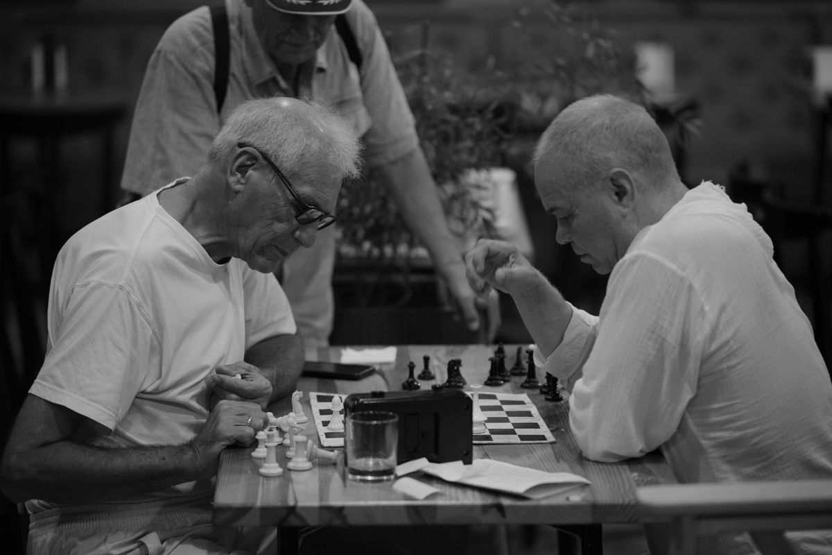 Seniors playing chess together in a café