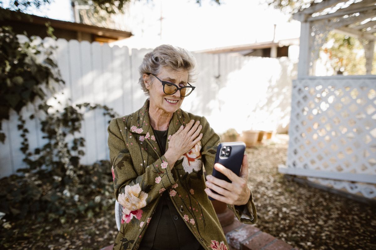 Senior woman smiling during a video call in a garden