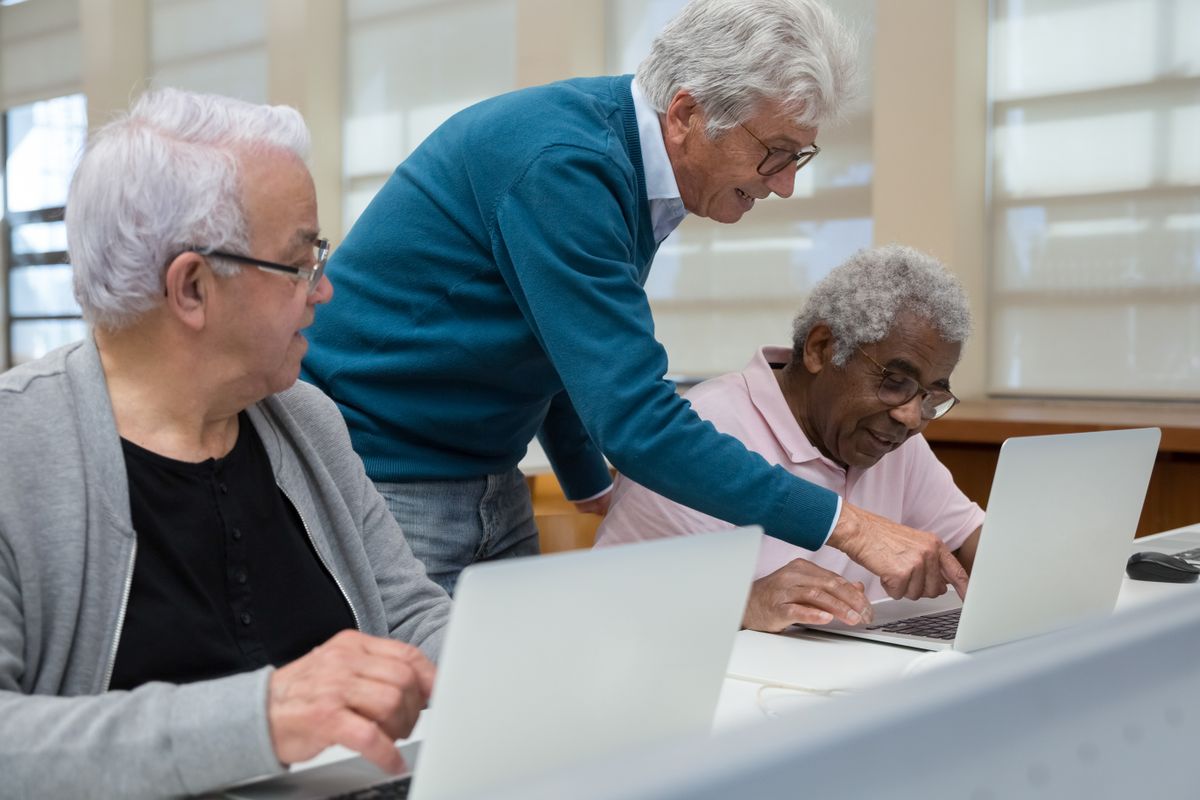Senior adults collaborating on laptops in a classroom